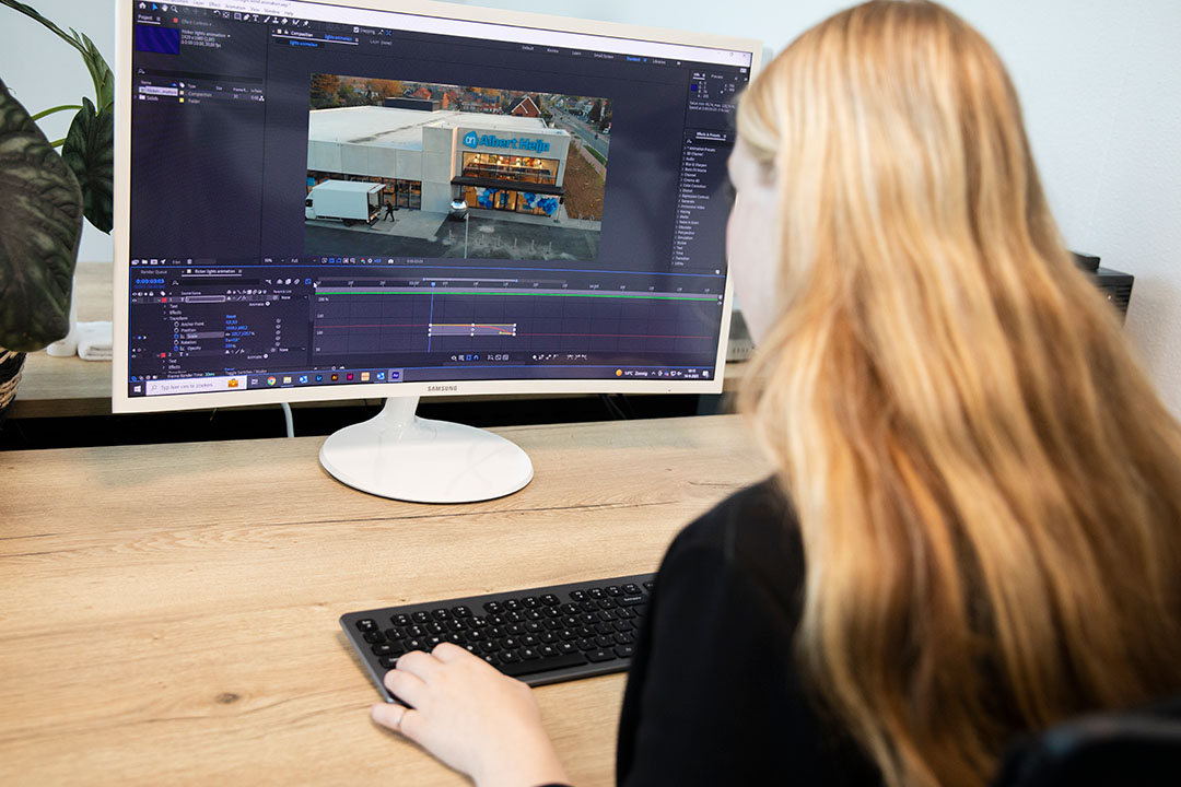 Grafisch ontwerper bij Marker Media werkt aan videomontage en animatie op een desktopcomputer.